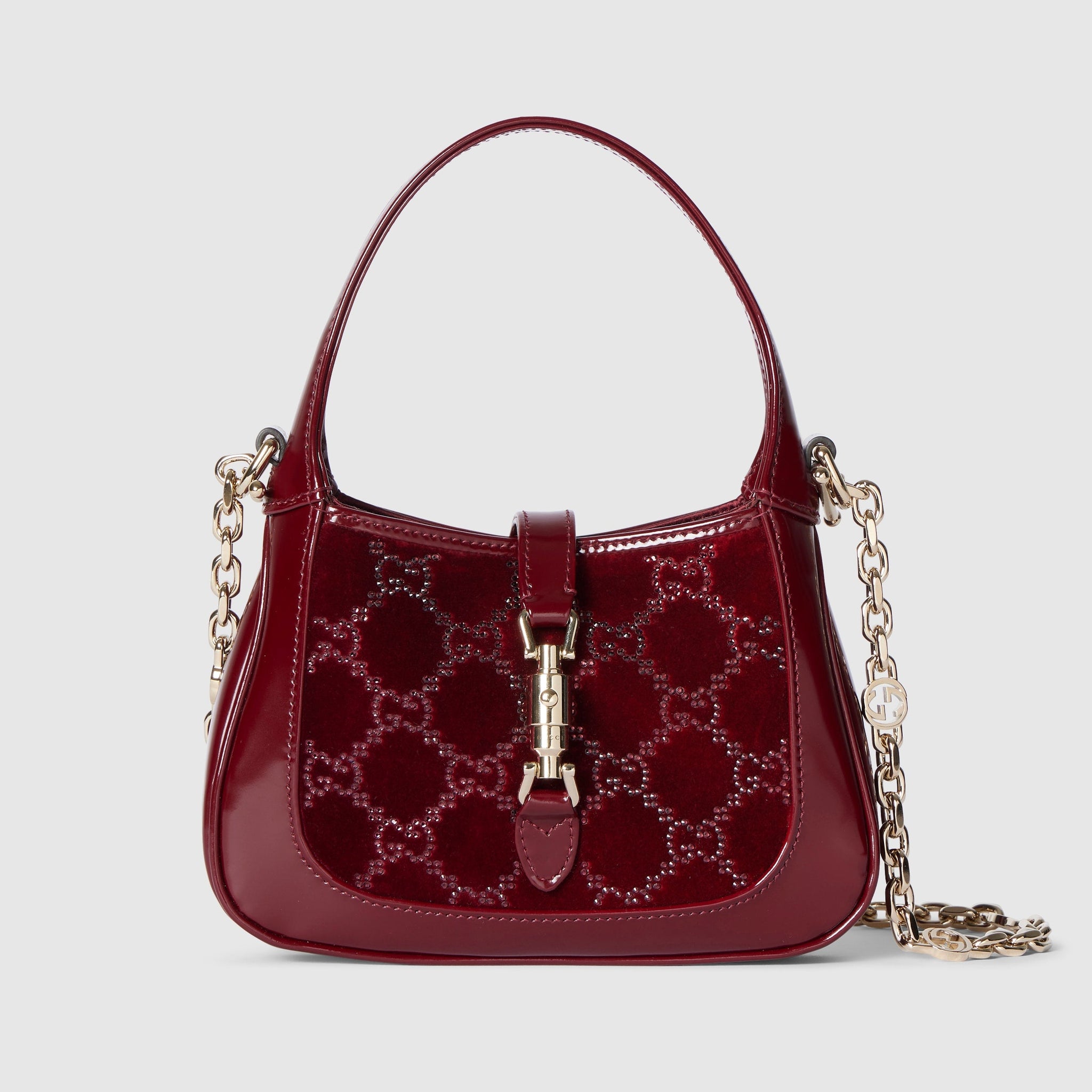 Red handbag with gold chain and clasp on a light gray background