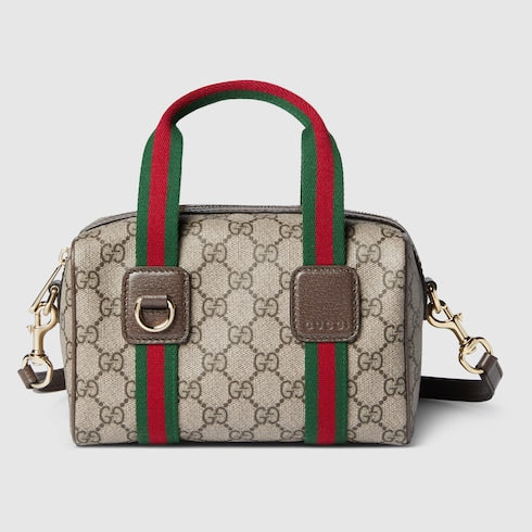 Designer handbag with red and green striped handle on a light gray background